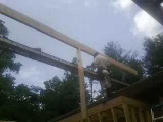 Carpenter setting a ridge beam over a new addition frame — Ice Dam Removal by Roofing Brothers in Red Springs