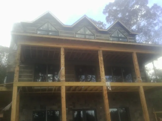 Dormers and porch framing on a large log home under construction — Roof Coating work by our crew in Red Springs