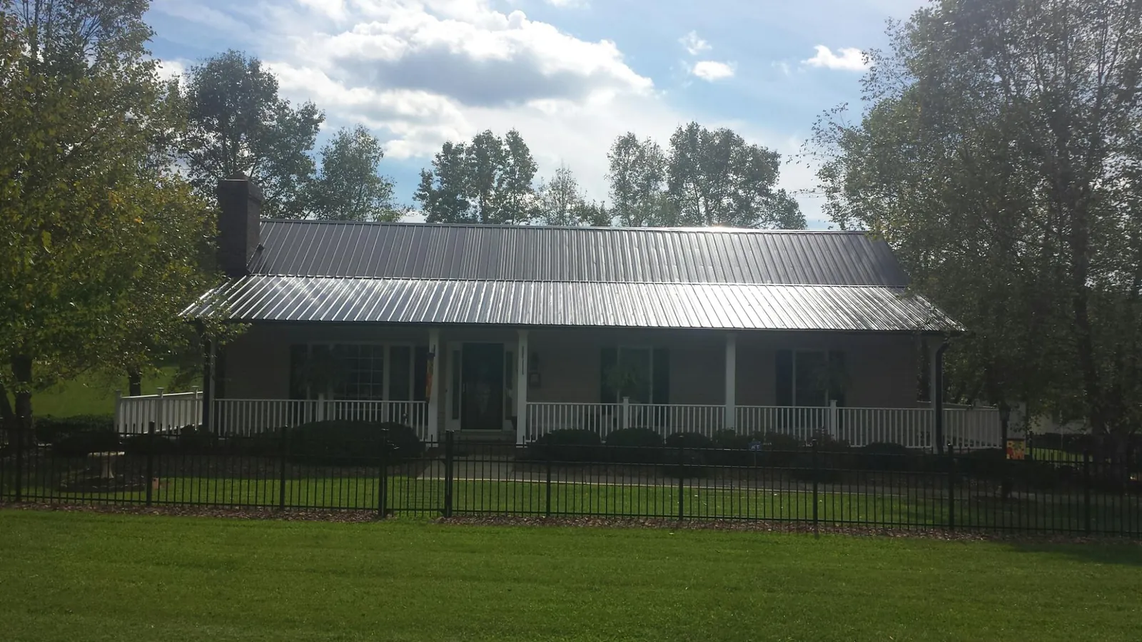 Gray metal roof on a brick ranch with a full width front porch — Gutter Guard Installation work by our crew in Red Springs