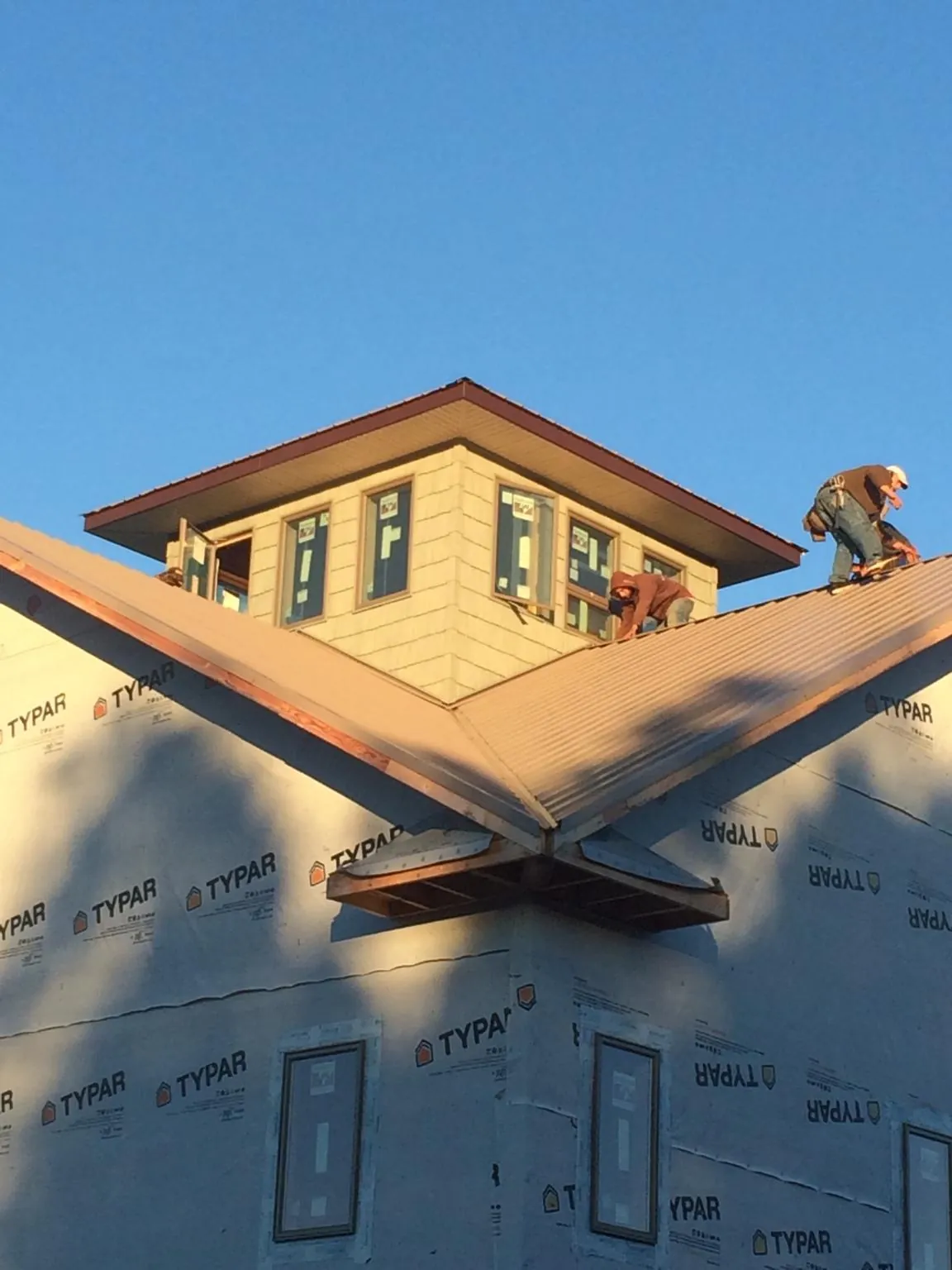 Roofers working around a rooftop cupola on a new metal roof at sunset — Roof Waterproofing in Red Springs by Roofing Brothers